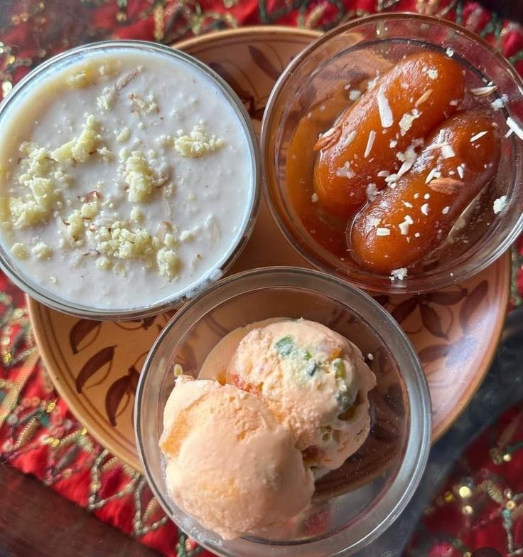 three small bowls filled with food on top of a wooden table next to an orange and white plate