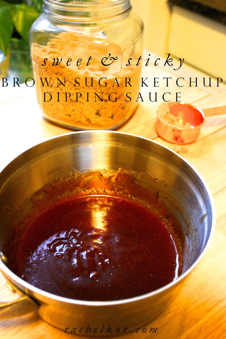 a metal bowl filled with brown sugar next to a jar of dipping sauce on top of a wooden table