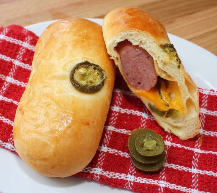 a hot dog sandwich with jalapenos on a red and white checkered napkin