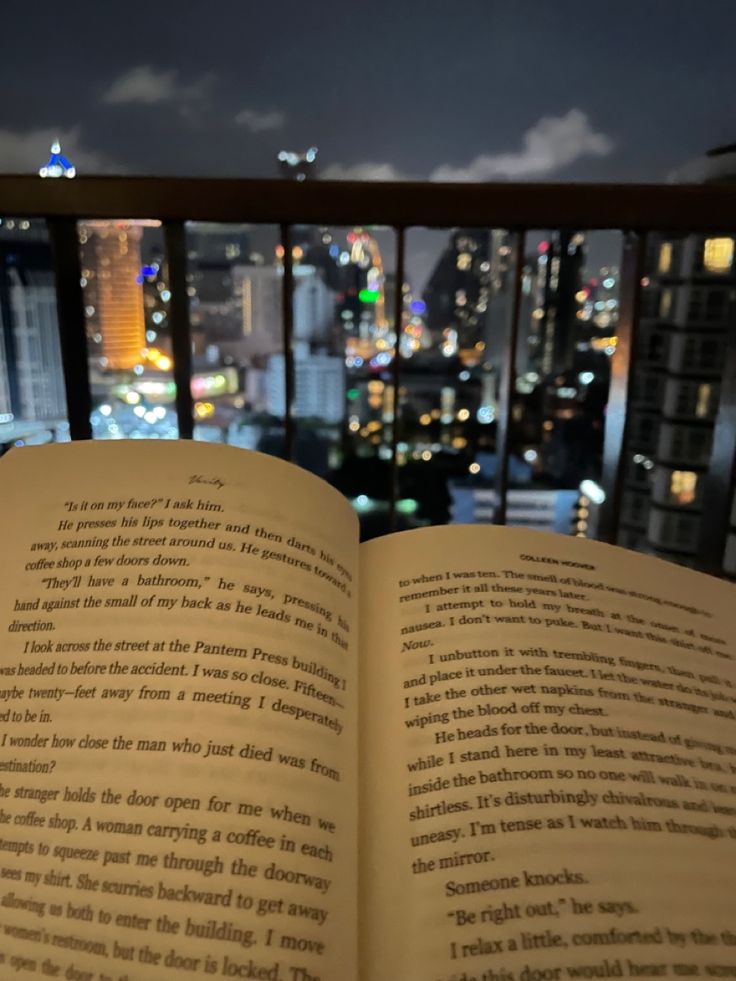 an open book sitting on top of a table in front of a cityscape