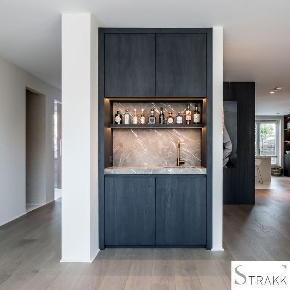 a kitchen with black cabinets and marble counter tops in the middle of an open floor plan