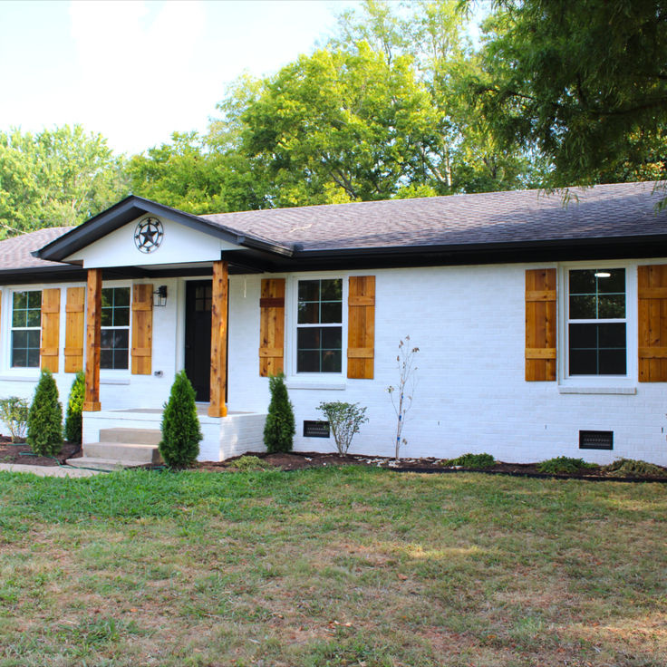 a white house with wooden shutters and green grass