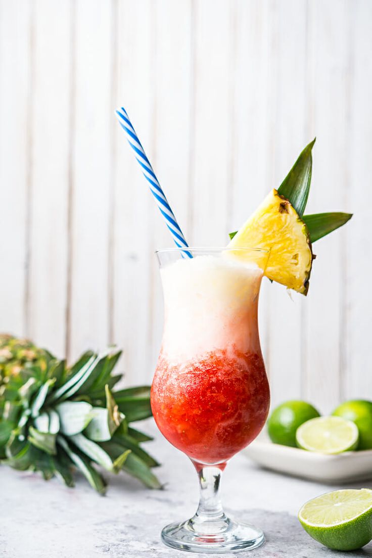 a drink in a glass with a blue and white striped straw garnish on the rim