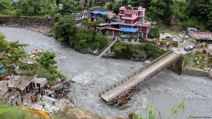 a river running through a lush green forest filled with lots of buildings and people standing on top of it