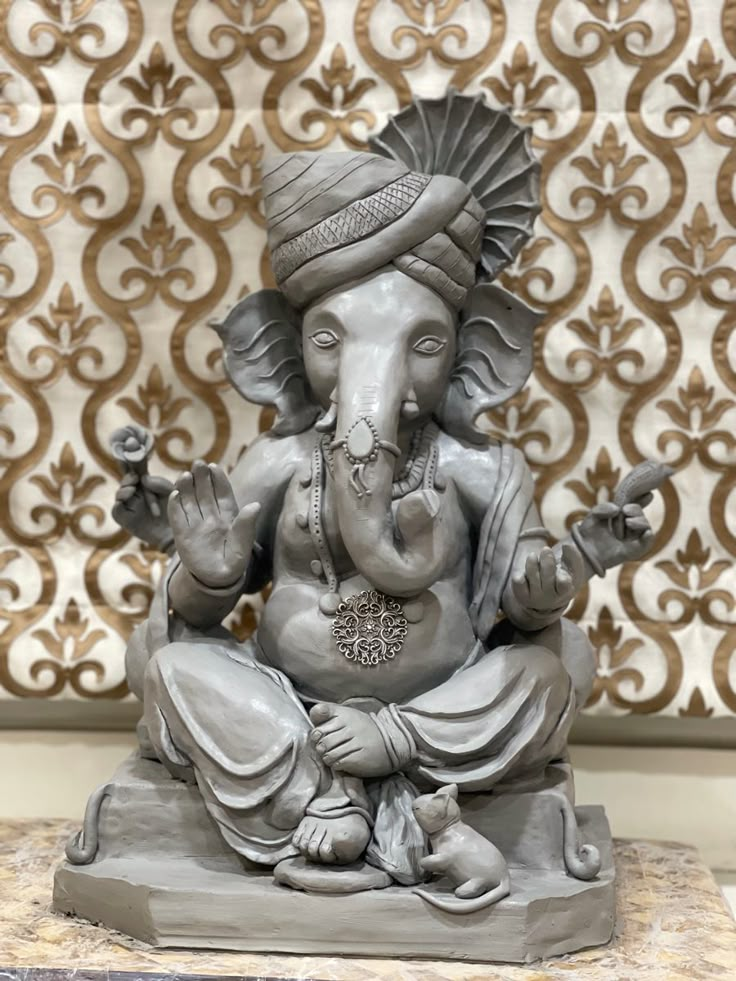 an elephant statue sitting on top of a table next to a wallpapered background