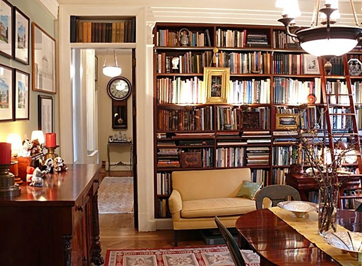 a living room filled with lots of furniture and bookshelves next to a doorway