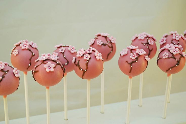 cake pops with pink frosting and flowers on top are lined up in rows, ready to be eaten