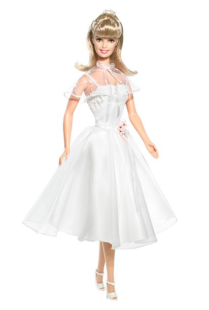 a barbie doll wearing a white dress and high heeled shoes is standing in front of a white background