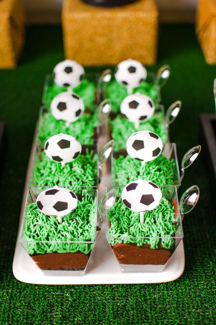 a table topped with cupcakes covered in green frosting and soccer balls on them