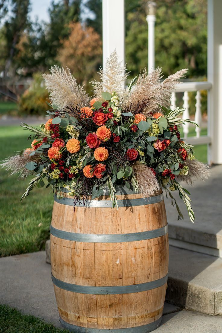 a wooden barrel filled with lots of flowers and greenery sitting on the side of a house