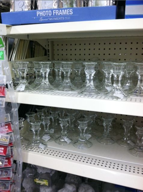 many empty glasses are on display in a glass store shelf with other items behind them