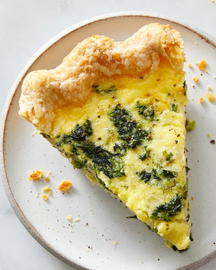 a slice of quiche with spinach and cheese on a plate