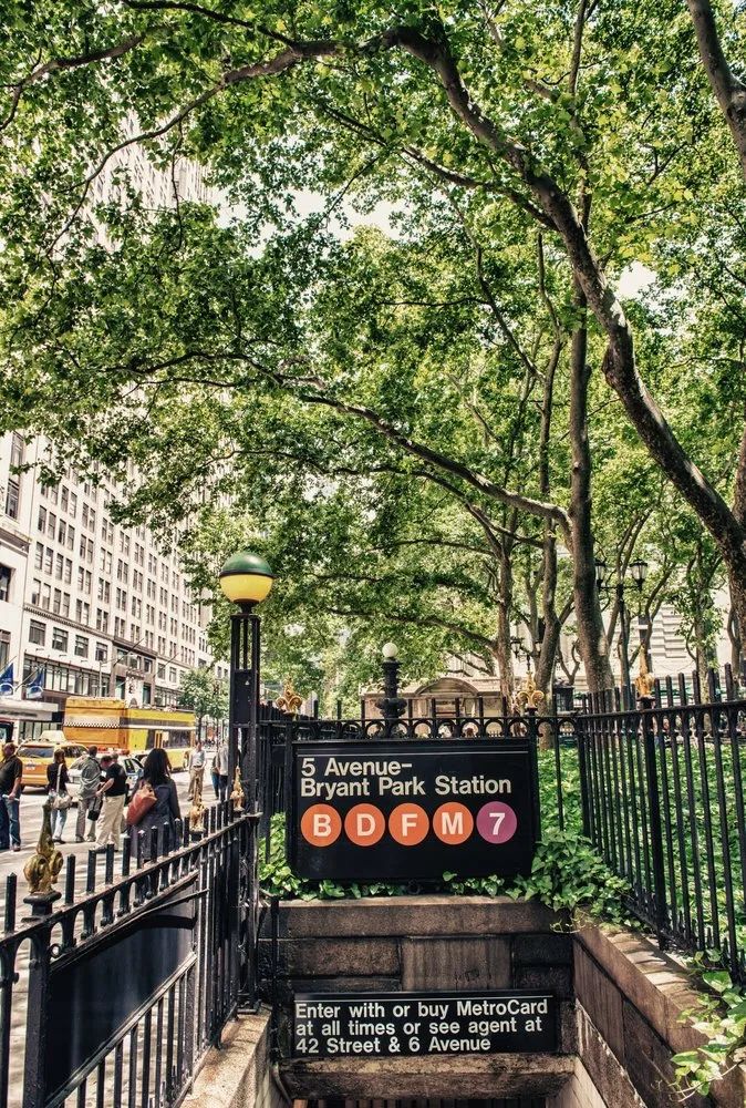 an entrance to the new york public library with trees and people walking on the sidewalk