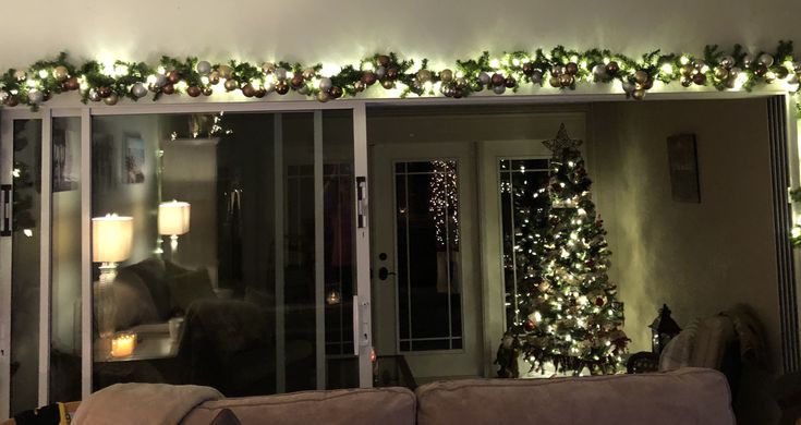 a living room decorated for christmas with lights and greenery on the windowsills