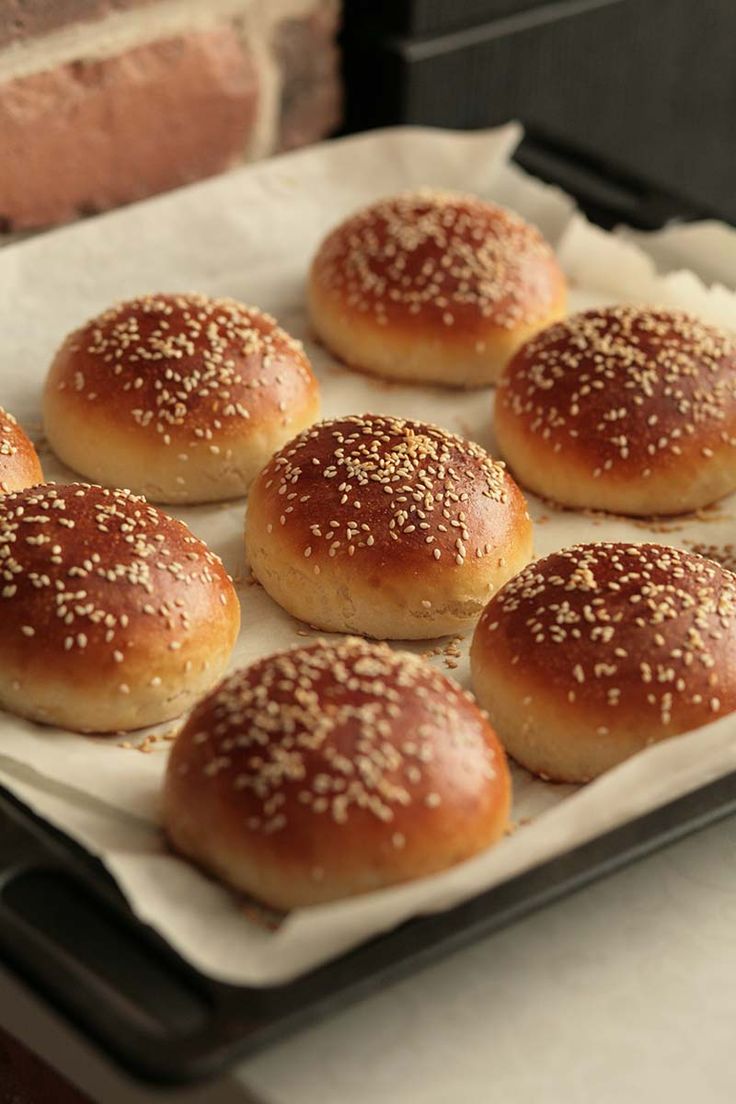 small buns with sesame seeds sit on a baking sheet