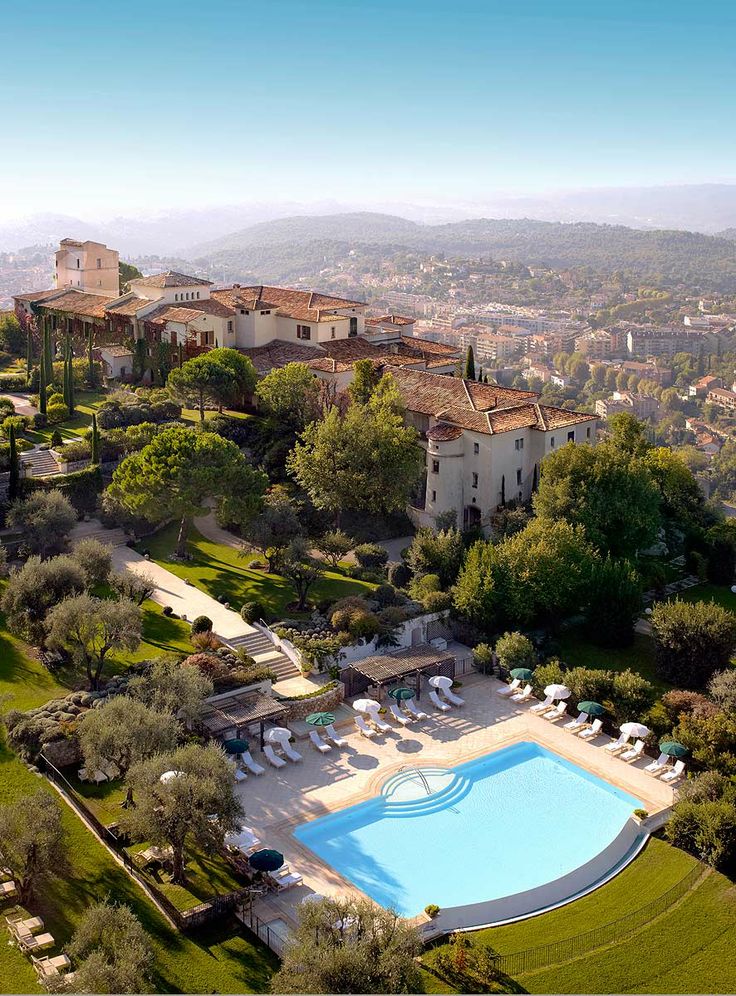 an aerial view of a large pool surrounded by lush green trees and buildings in the distance