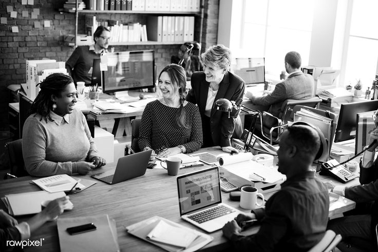 a group of people sitting around a table working on laptops