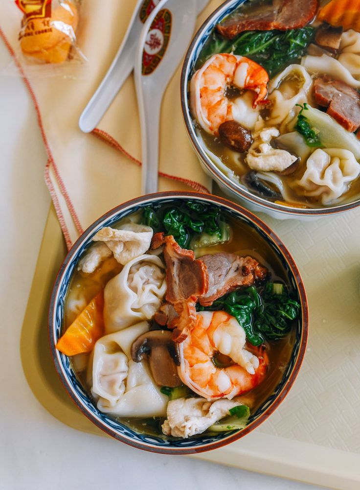 two bowls filled with soup on top of a cutting board