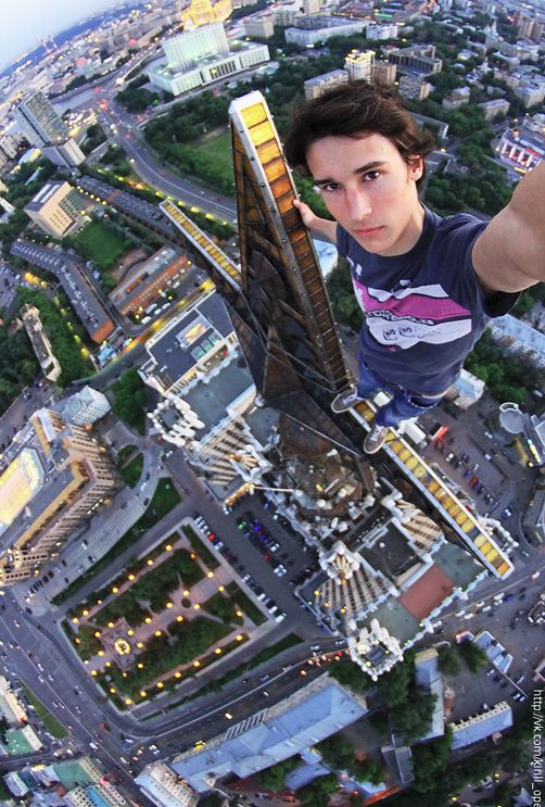 a man flying through the air on top of a tall building next to a city