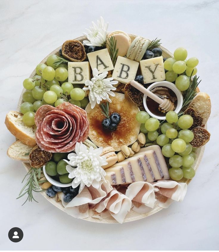 a platter filled with cheese, crackers, grapes and baby blocks on top of each other