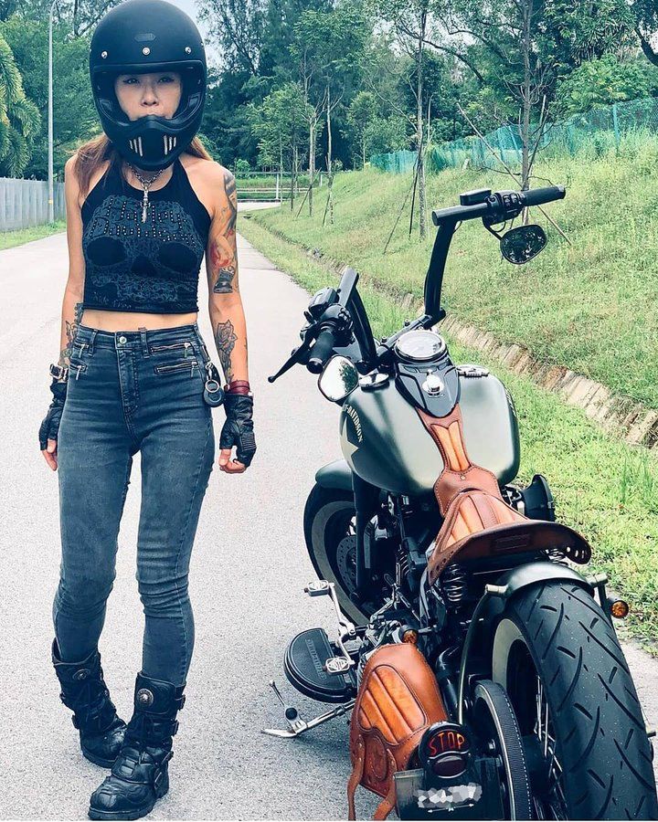 a woman standing next to a motorcycle on the road