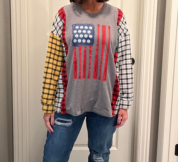 a woman standing in front of a door wearing an american flag shirt and ripped jeans