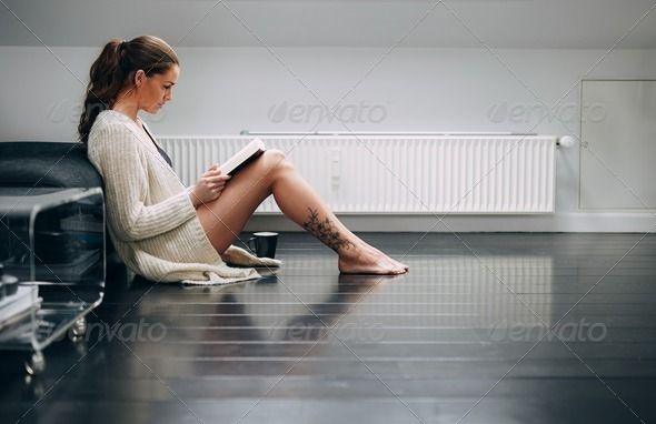 a woman sitting on the floor with her legs crossed and looking at something in front of her