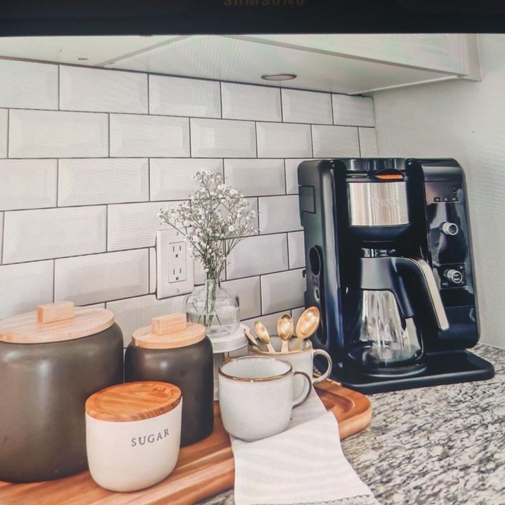 there is a coffee maker on the counter next to two mugs and a blender