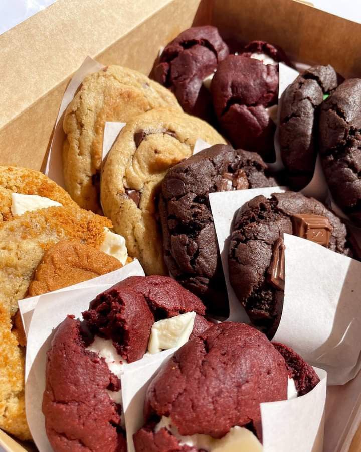 a box filled with assorted cookies and muffins on top of each other