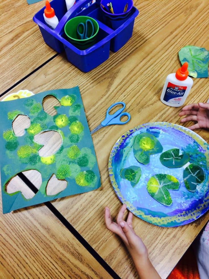 a child is making a paper plate shamrock art project with glue and watercolors