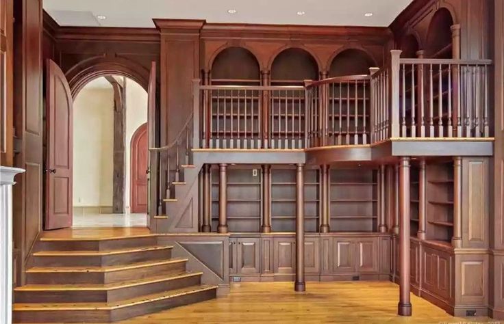 a large wooden room with stairs and bookshelves