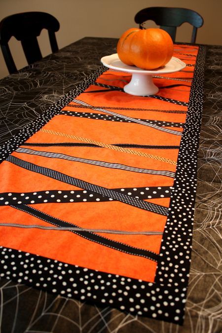 an orange and black table runner on top of a dining room table with polka dots