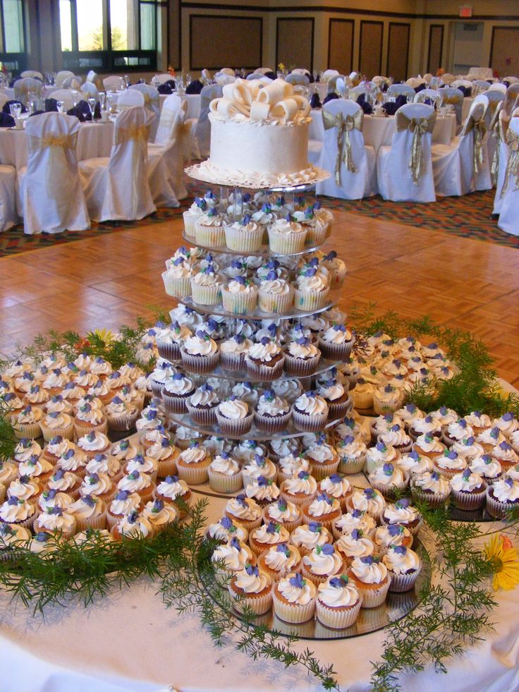 a wedding cake and cupcakes are arranged in the shape of a pyramid on a table