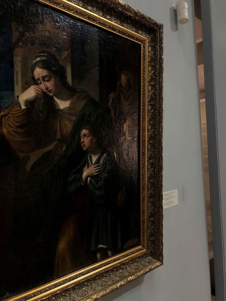 a painting hanging on the wall next to a woman holding a child's hand