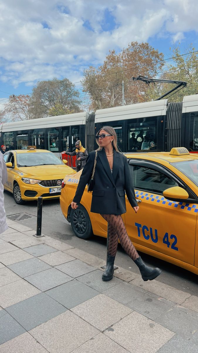 a woman is walking in front of a taxi