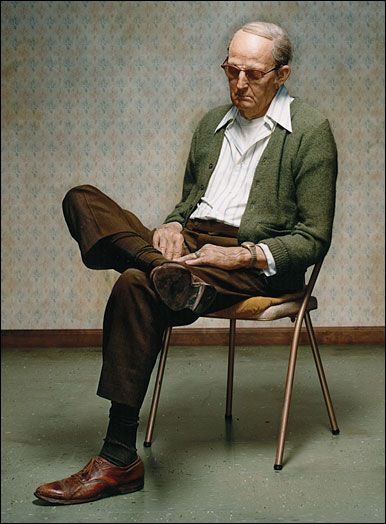 an old man sitting in a chair with his legs crossed