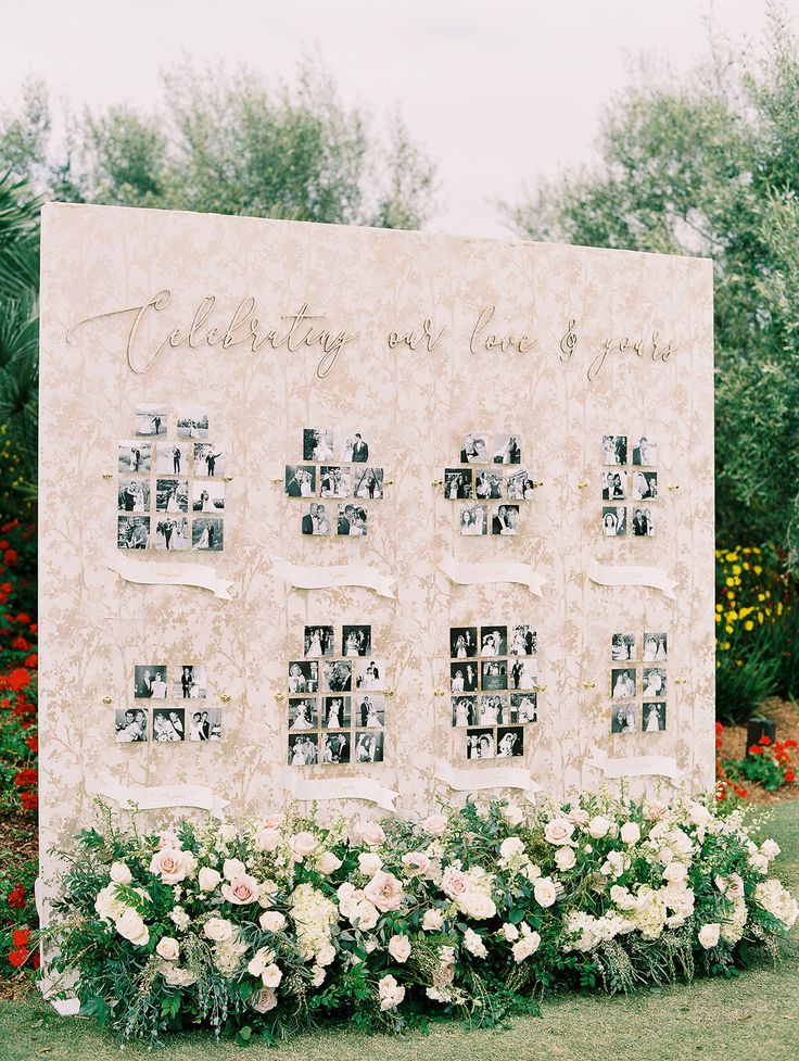 a large sign with pictures on it in front of some flowers and trees at an outdoor wedding