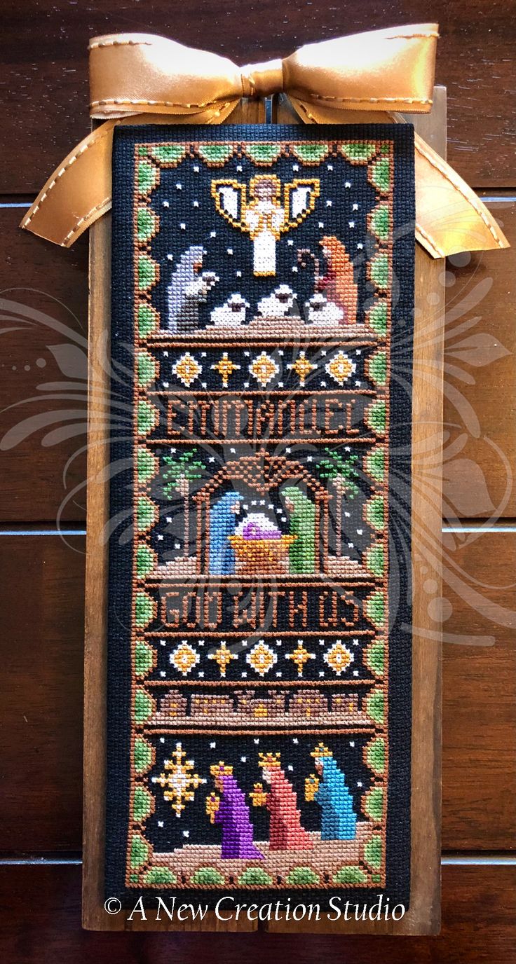 the cross stitch sample is hanging on a wooden wall with a ribbon around it's edge