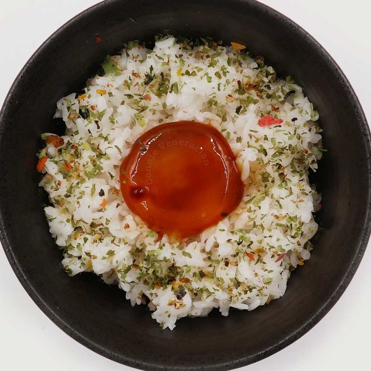 a black bowl filled with rice and sauce