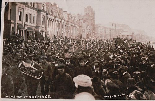 an old black and white photo of a crowd of people in front of some buildings