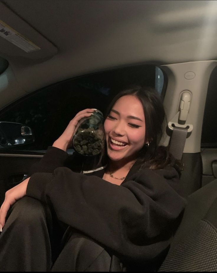 a woman sitting in the back seat of a car holding up a stuffed animal to her face