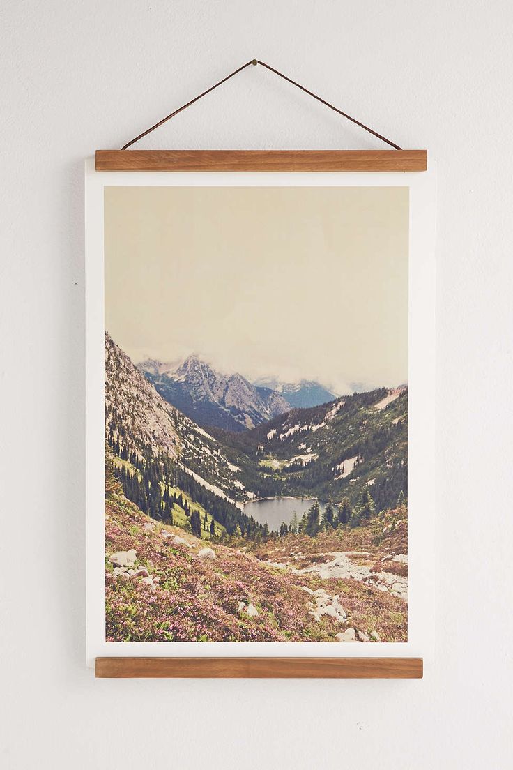 a wooden frame hanging on the wall displaying a photograph of a mountain lake and mountains