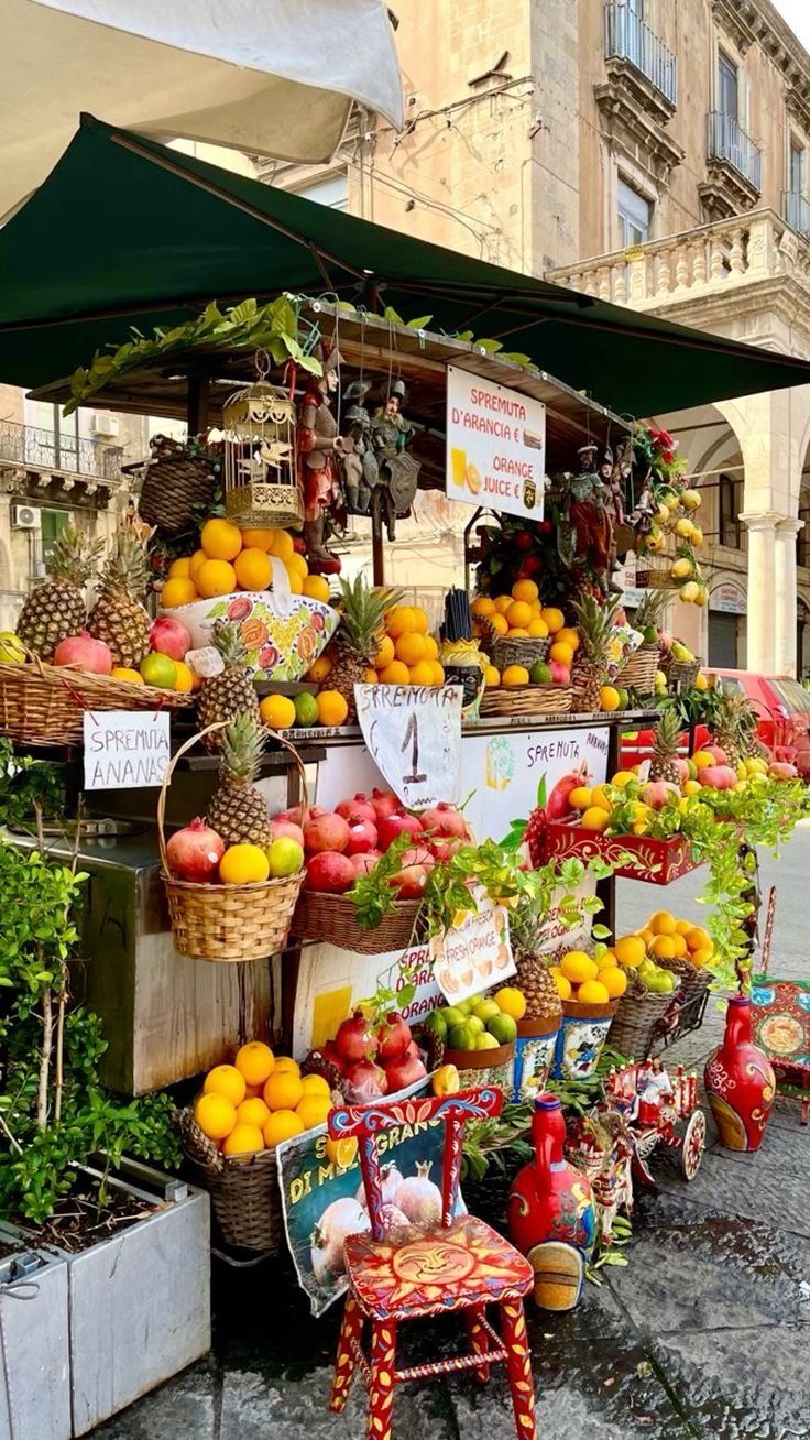 an outdoor fruit stand with lots of fruits and vegetables on it's display shelf