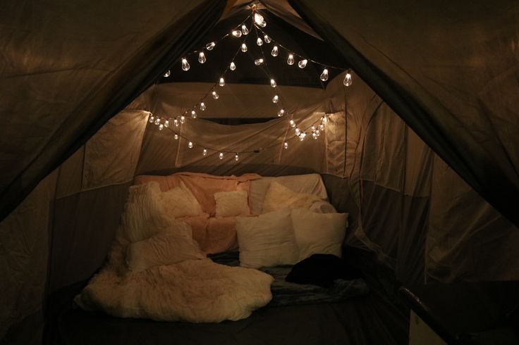 a bed with pillows and lights in a tent