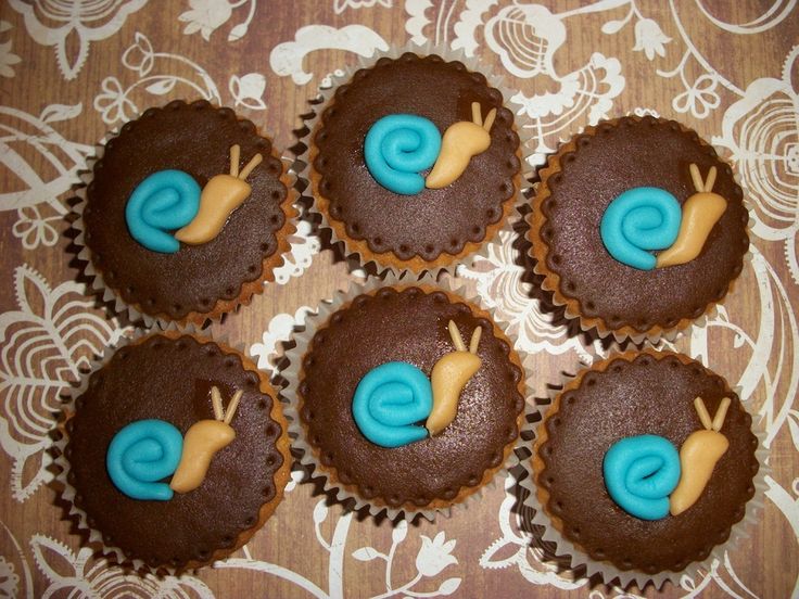 four chocolate cupcakes with blue icing and snail decorations