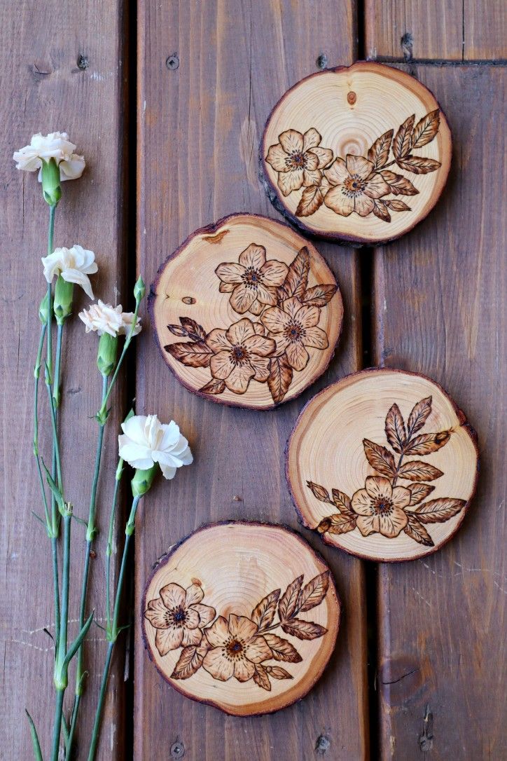 three wood slices with flowers on them sitting on a wooden table next to some white flowers