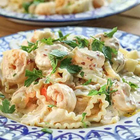 two plates of pasta with shrimp and parsley