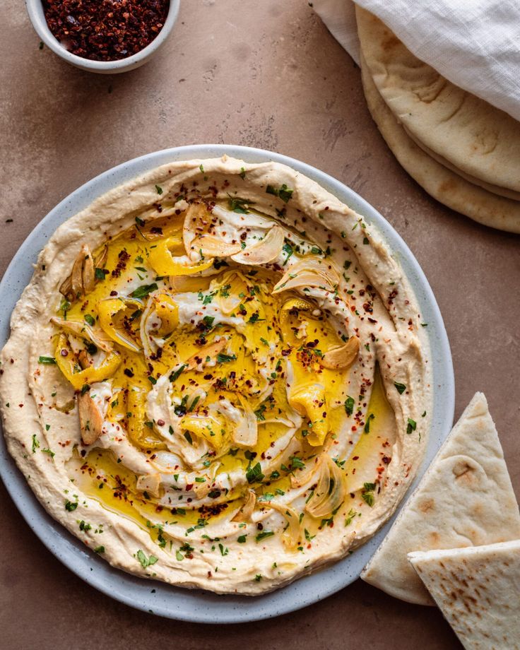 hummus and pita bread on a plate next to a bowl of seasoning