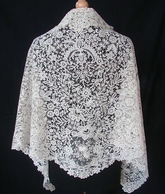 a white lace shawl is shown on a mannequin headdress and black background