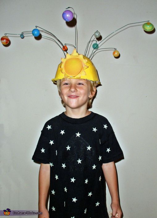 a young boy wearing a yellow hat with planets on it's head and eyes